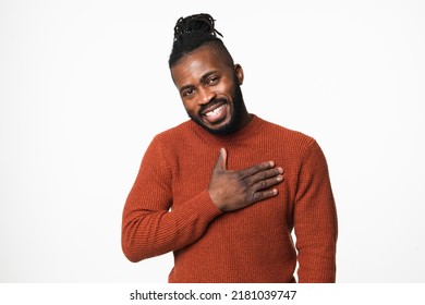 Cheerful Touched With A Compliment Happy Shy African-american Young Man In Red Sweater With Dreadlocks Looking At Camera With Toothy Smile Isolated In White Background