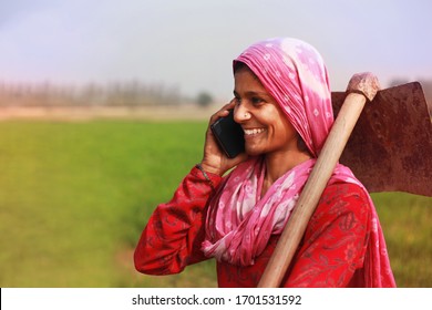 Cheerful traditional Village women standing in green wheat field and talking on the mobile phone. She looking so happy when she talking on the phone. 