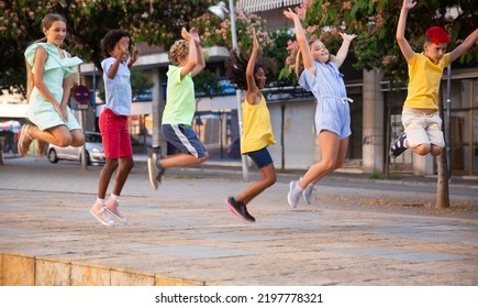 Cheerful Tween Girls And Boys Jumping Together On Summer City Street. Concept Of Happy Preadolescence..