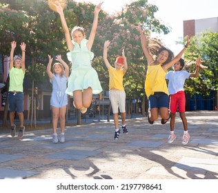 Cheerful Tween Girls And Boys Jumping Together On Summer City Street. Concept Of Happy Preadolescence..