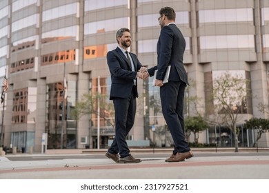 cheerful two business men handshaking. two business men handshaking outdoor.