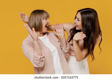 Cheerful two fun young smiling happy daughter mother together couple women in casual beige clothes open close eyes with hands play guess who or hide and seek isolated on plain yellow background studio
