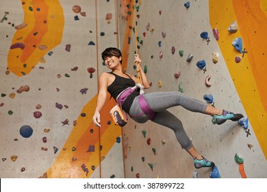 Cheerful Vietnamese girl practicing climbing on rock wall indoors - Powered by Shutterstock