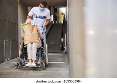 Cheerful volunteer laughing with a pensioner while looking at each other faces during a wheelchair ride from a supermarket - Powered by Shutterstock