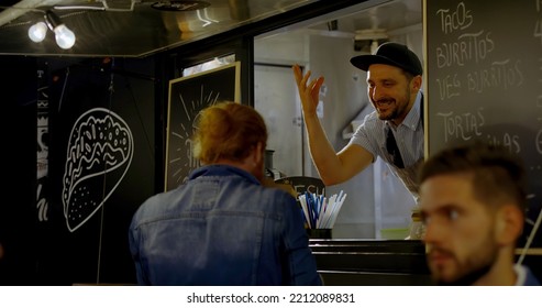 Cheerful waiter taking order from multi-racial customers at counter, Mexican street food served from a food truck - Powered by Shutterstock