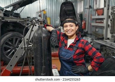 Cheerful woman auto mechanic standing in vehicle repair shop - Powered by Shutterstock