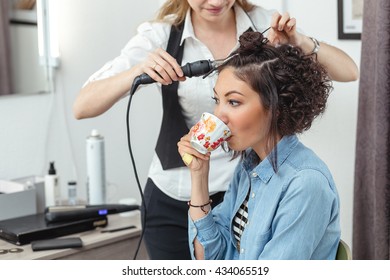 Cheerful Woman In The Barber Shop With Beautiful Unusual Curly Hair Drinking Coffee Or Tea. 