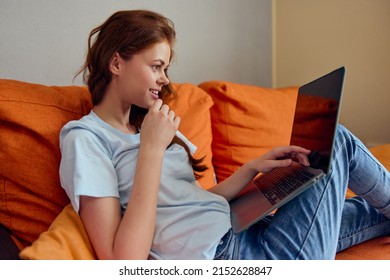 Cheerful Woman Chatting On The Orange Couch With A Laptop Lifestyle