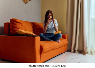 Cheerful Woman Chatting On The Orange Couch With A Laptop Apartments