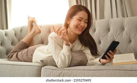 Cheerful Woman Chatting Online, Typing Text Message On Mobile Phone While Relaxing At Home In In Cozy Winter Or Autumn Weekend