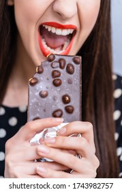 Cheerful Woman Eating Chocolate. Cropped Photo. Closeup. Black Chocolate With Nuts.