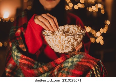 Cheerful woman eating popcorn and watches christmas comedy movie on cable TV at home in evening alone, close-up. Christmas traditions concept - Powered by Shutterstock