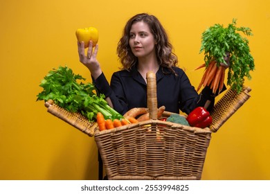  A cheerful woman holding a picnic basket brimming with fresh fruits and vegetables, radiating health and wellness. The vibrant yellow background enhances the lively, joyful atmosphere of the scene. - Powered by Shutterstock