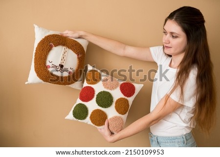 Cheerful woman holding pillows. Punch needle embroidery pillow diy. Product is made according to the technique pushing woolen threads on foundation fabric with needle with wood handle