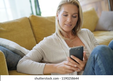 Cheerful woman at home using smartphone - Shutterstock ID 1190258644