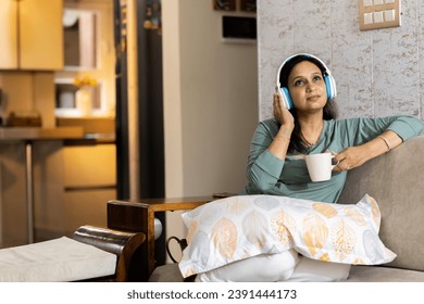 Cheerful woman listening music while drinking coffee at home - Powered by Shutterstock