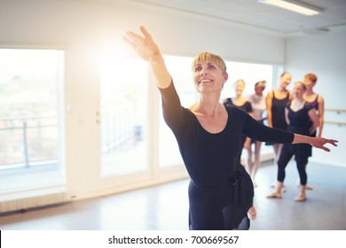 Cheerful woman performing a ballet dance in adult group in class.
