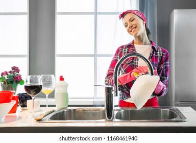 Cheerful woman in pink protective rubber gloves washes plate in the kitchen - Powered by Shutterstock