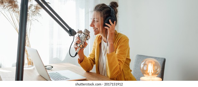 Cheerful Woman Podcaster Recording Her Voice Into Microphone. Female Radio Host Streaming Podcast Using Microphone And Laptop At His Home Studio