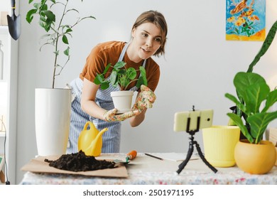 Cheerful woman recording video blog about home gardening on her smartphone, showcasing her hobby and care for nature to online followers. Online communication, blogging concept - Powered by Shutterstock