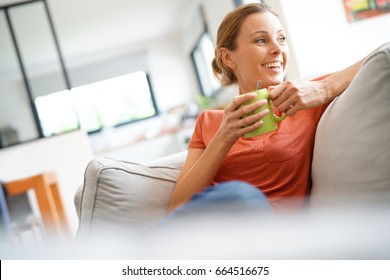 Cheerful Woman Relaxing In Sofa And Drinking Tea