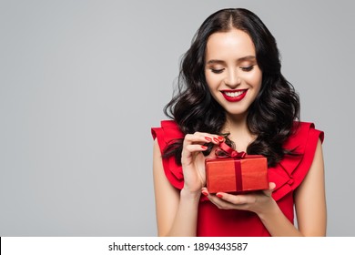 Cheerful Woman In Ruffled Dress Pulling Ribbon On Gift Box Isolated On Grey