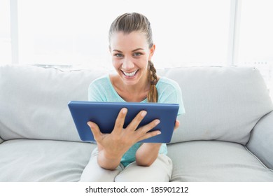 Cheerful Woman Sitting On Couch Using Tablet Pc At Home In The Living Room