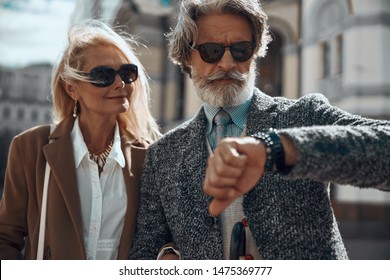 Cheerful Woman Smiling And Looking At The Watch Of Her Serious Husband