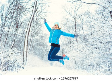 Cheerful Woman In Sports Clothing Enjoying The Winter And Snow Jumping High