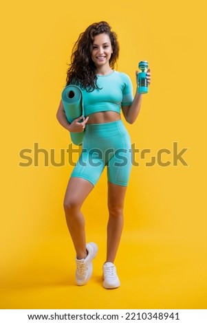 cheerful woman in sportswear with fitness mat and sport bottle in studio. fitness woman