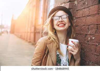 Cheerful woman in the street drinking morning coffee in sunshine light