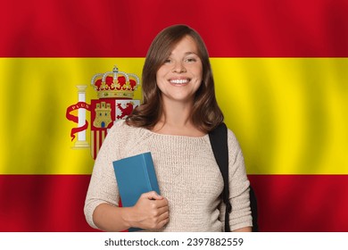 Cheerful woman student against Spanish flag background. Travel, education and learn language in Spain concept