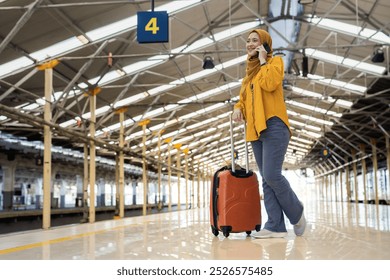 Cheerful Woman Talking on Phone at Train Station. A confident woman in a yellow hijab smiles while talking on her phone at the train station, exuding joy and excitement for travel. - Powered by Shutterstock