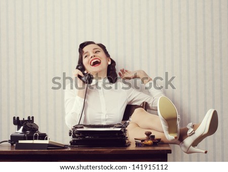 Cheerful woman talking on phone at desk