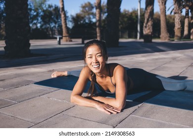 Cheerful Woman In Tracksuit Stretching Legs And Pelvic Floor Muscles Practice Twine During Pilates Workout At Street, Portrait Of Joyful Fit Girl Making Effort For Getting To Sportive Physical Goal