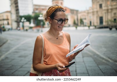 Cheerful woman wander with travel guidebook and smart phone