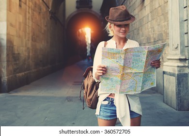Una mujer alegre vagabunda con una mirada de moda buscando dirección en el mapa de ubicación mientras viaja al extranjero en verano, feliz mujer turista camino a hotel en atlas en una ciudad extranjera durante las vacaciones