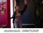 Cheerful woman waving hand while entering to pub