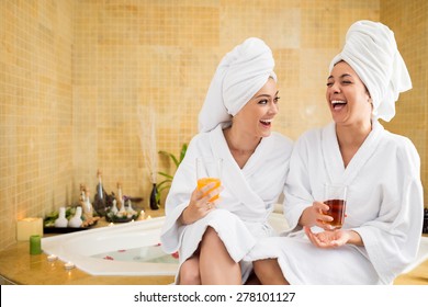 Cheerful Women In Bathrobes Drinking Juice: Friends In Spa Salon
