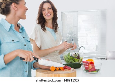 Cheerful women preparing salad together  in the kitchen 