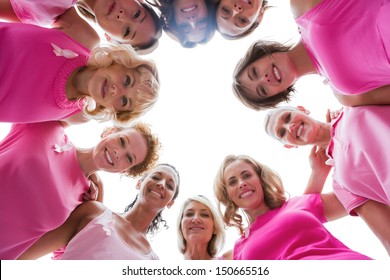 Cheerful women smiling in circle wearing pink for breast cancer on white background
