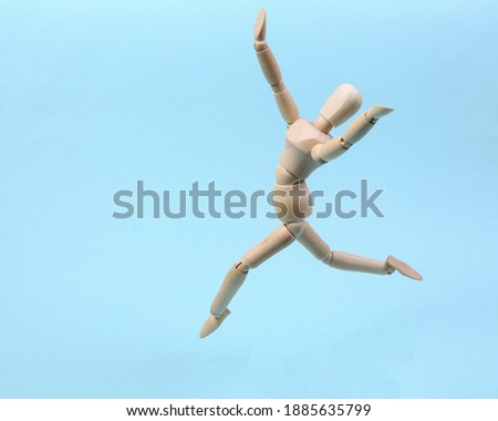 Cheerful wooden puppet jumping on blue background