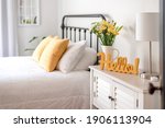 Cheerful yellow hello sign and fresh flowers in a clean and bright bedroom