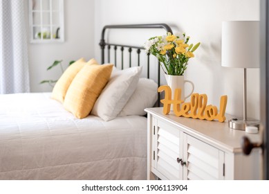 Cheerful yellow hello sign and fresh flowers in a clean and bright bedroom