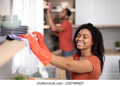 Cheerful young african american couple in same t-shirts wipes dust from furniture together in kitchen interior. Household chores, house cleaning in free time, couple enjoy housework due covid-19 - Powered by Shutterstock