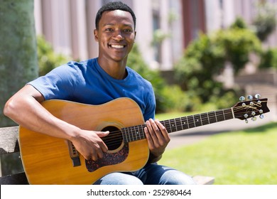 Cheerful Young African American Man Playing Guitar Outdoors