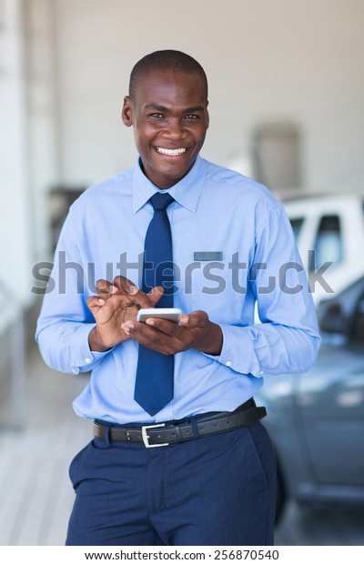 cheerful\
young african car salesman using smart\
phone