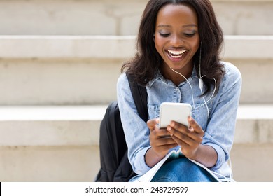 Cheerful Young African College Girl Using Smart Phone Listening Music