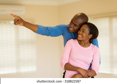 cheerful young african couple looking round their new house