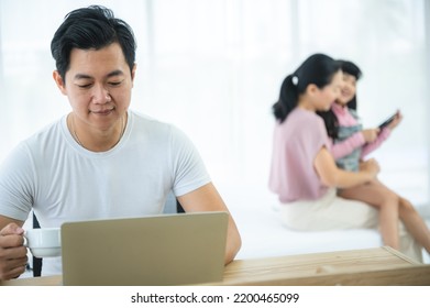 Cheerful Young Asian Family Of Handsome Father And Beautiful Mother Lying On Bed With Cute Little Daughter Laughing While Watching A Comedy Movie On Laptop And Relaxing At Home